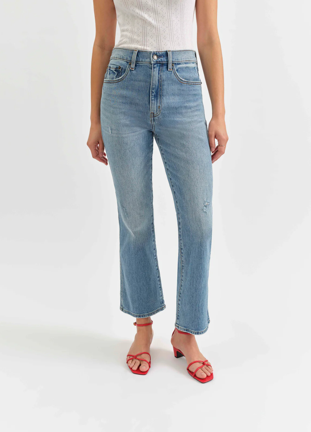 Person wearing blue jeans and red sandals on a white background